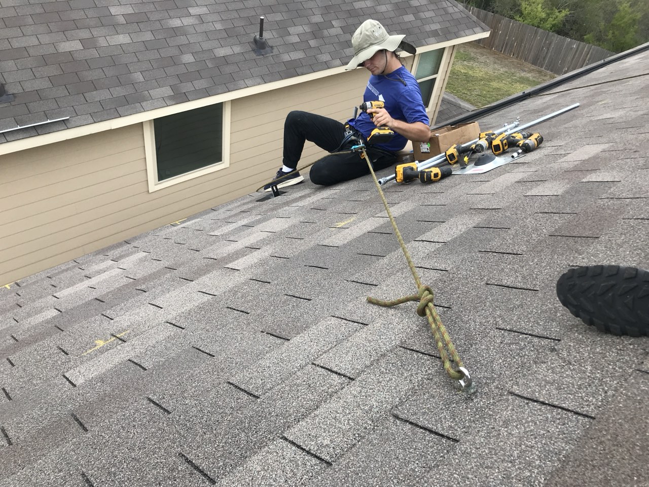 Technician roped in with fall protection on a shingle roof